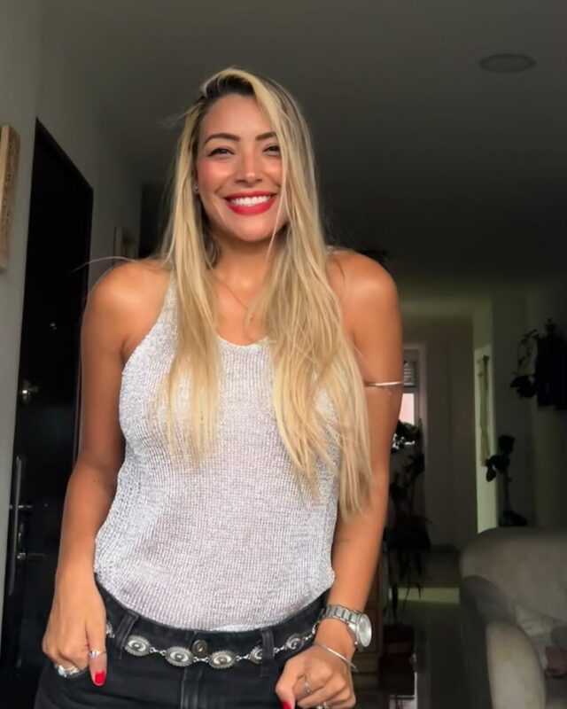 Retrato de Débora Arboleda, DebAnanda, de pie y sonriendo en un espacio interior