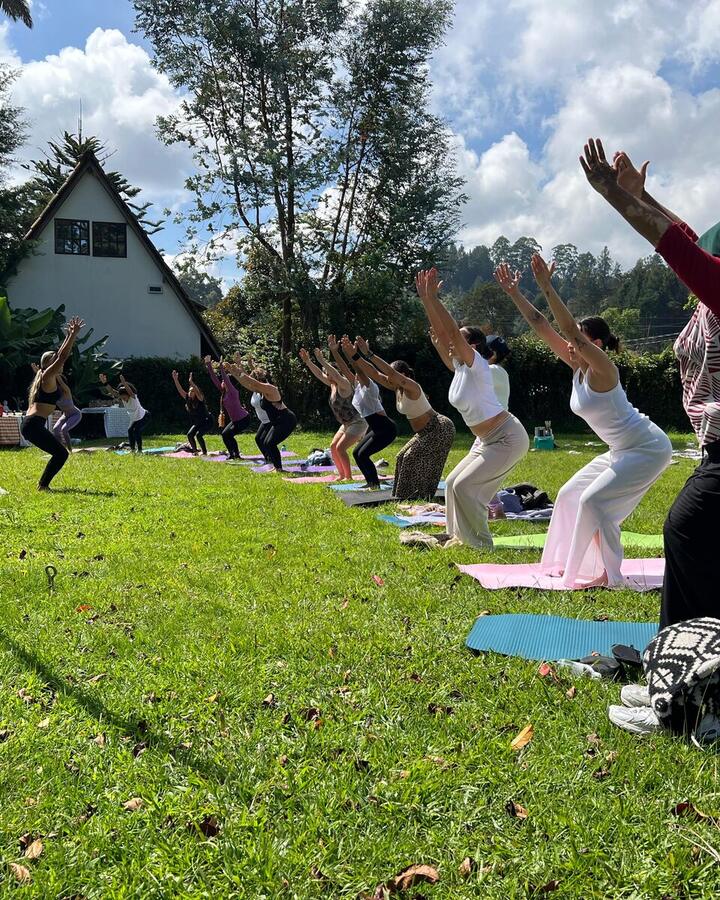 Clase de yoga al aire libre en un jardín: alumnas en postura del guerrero