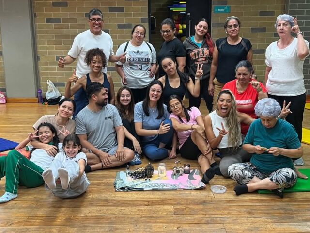 Grupo de mujeres reunido en círculo alrededor de un altar con velas, aceites y una figura de Buda.