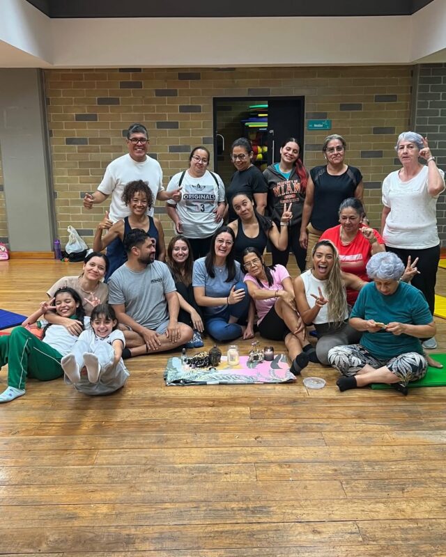 Grupo de mujeres reunido en círculo alrededor de un altar con velas, aceites y una figura de Buda.